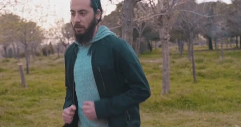 Long haired and bearded handsome sportive guy is running on grass, forest in  Stock Footage 151644810