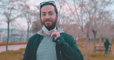 Long haired and bearded young handsome guy is taking off his face mask and dr Stock Footage 151609525
