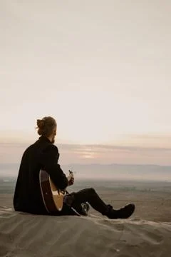 Long haired bearded guy with guitar sitting in the sunset Stock Photos