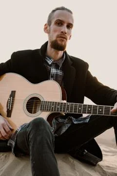 Long haired bearded guy with guitar sitting in the sunset Stock Photos