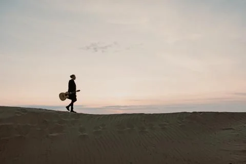 Long haired bearded guy with guitar standing in the sunset Foto stock