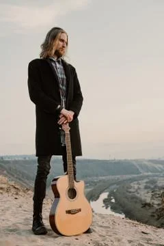 Long haired bearded guy with guitar standing in the sunset Stock Photos