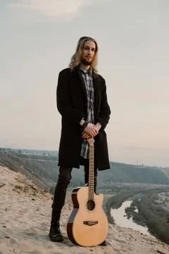 Long haired bearded guy with guitar standing in the sunset Stock Photos