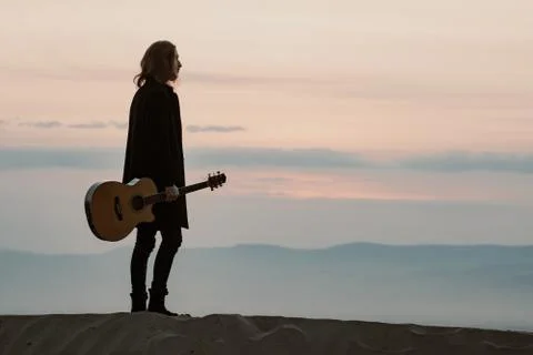 Long haired bearded guy with guitar standing in the sunset Stock Photos