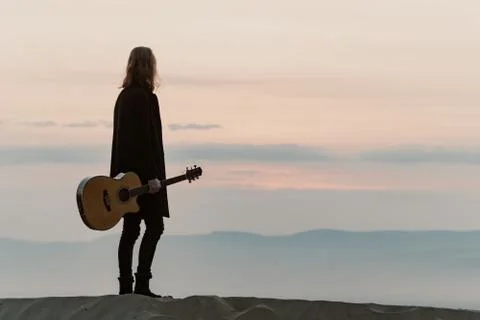 Long haired bearded guy with guitar standing in the sunset Stock Photos