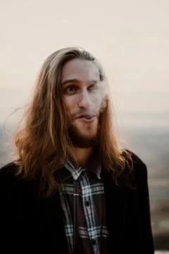 Long haired bearded guy smoking pipe in the sunset Stock Photos