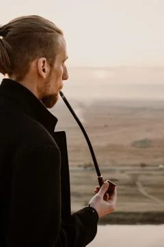 Long haired bearded guy smoking pipe in the sunset Stock Photos