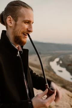 Long haired bearded guy smoking pipe in the sunset Stock Photos