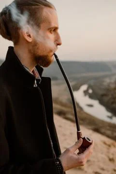 Long haired bearded guy smoking pipe in the sunset Stock Photos