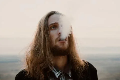 Long haired bearded guy smoking pipe in the sunset Stock Photos