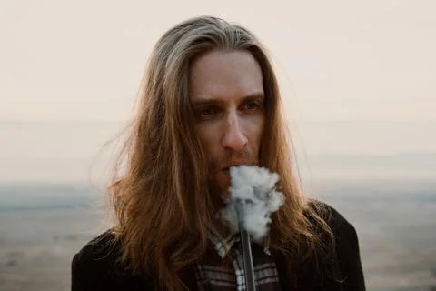 Long haired bearded guy smoking pipe in the sunset Stock Photos