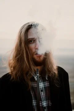 Long haired bearded guy smoking pipe in the sunset Foto stock