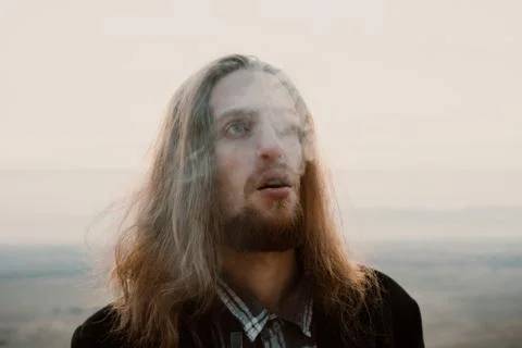 Long haired bearded guy smoking pipe in the sunset Stock Photos