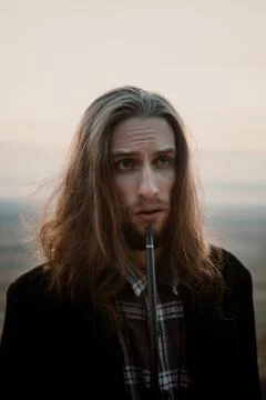 Long haired bearded guy smoking pipe in the sunset Stock Photos