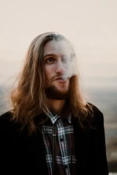 Long haired bearded guy smoking pipe in the sunset Stock Photos
