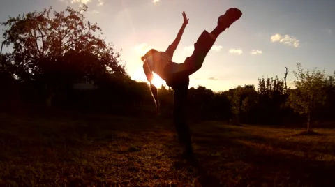 Long haired bearded men flying over the sun, doing acrobatic jump butterfly jump Stock Footage 66583618
