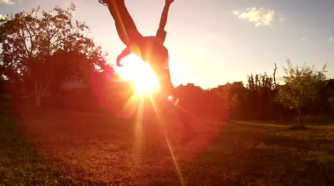 Long haired bearded men flying over the sun, doing acrobatic jump in slow motion Stock Footage 66584243
