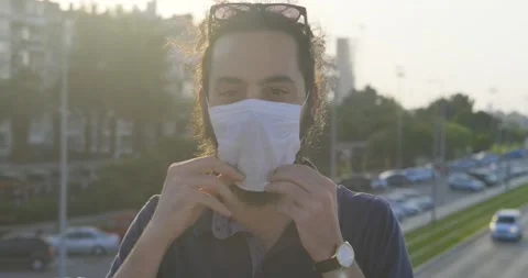 Long haired, bearded young handsome man is wearing face mask and smile. Prote Stock Footage 139298707