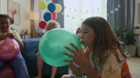 Long-haired Boy Blowing up Green Balloon while Preparing for Birthday Party Vídeo Stock 295284338
