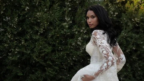 Long haired bride in lacy wedding dress walks in green park Video stock 126047033