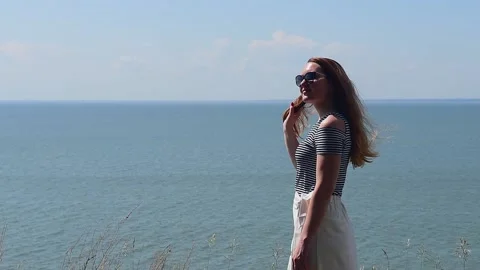 Long-haired brunette against the sea, her hair developing in the wind. Stock Footage 164419084