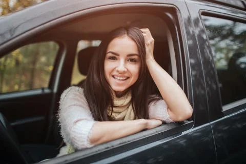 Long-haired brunette on the auto background. A female model is wearing a sweater Stock Photos