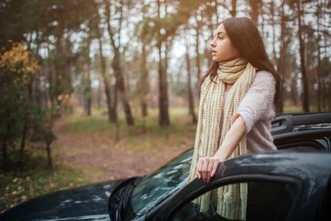 Long-haired brunette on the auto background. A female model is wearing a sweater 库存照片