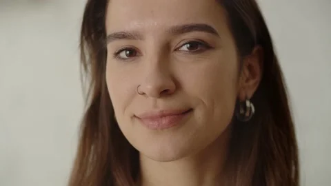 The long-haired brunette looks at the camera and begins to smile. Smiling Stock Footage 235784848