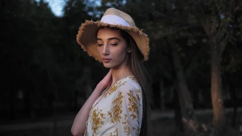 Long haired brunette in straw hat stands in dense forest Stock Footage 121060840