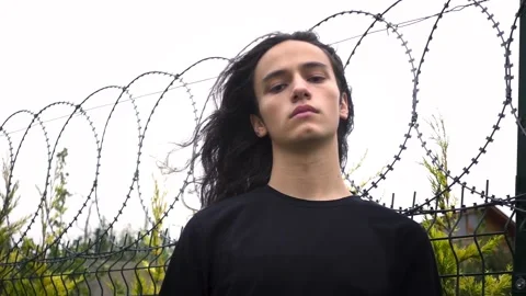 Long haired cool young protest man with black shirt standing staring in front Stock Footage 160194228