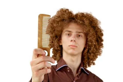 A long-haired curly-haired guy in a brown shirt on a white background uses a  Stock Photos