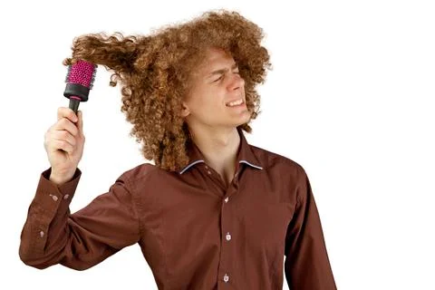 A long-haired curly-haired guy in a brown shirt on a white background uses a  Stock Photos