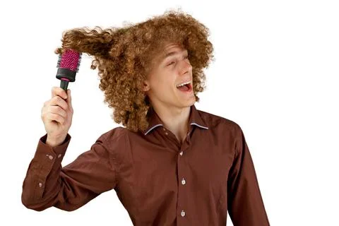 A long-haired curly-haired guy in a brown shirt on a white background uses a  Stock Photos