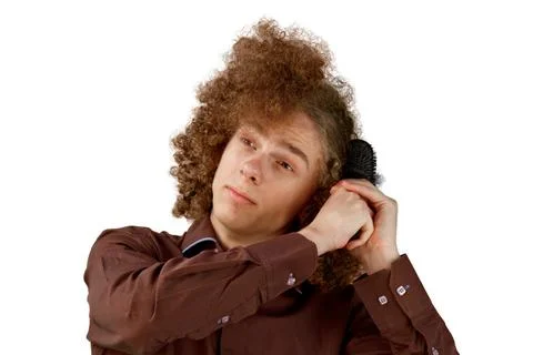 A long-haired curly-haired guy in a brown shirt on a white background uses a  Stock Photos