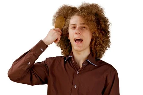 A long-haired curly-haired guy in a brown shirt on a white background uses a  Stock Photos