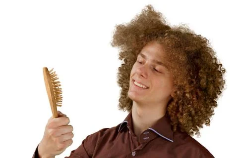 A long-haired curly-haired guy in a brown shirt on a white background uses a  Stock Photos