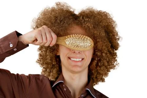 A long-haired curly-haired guy in a brown shirt on a white background uses a  Stock Photos