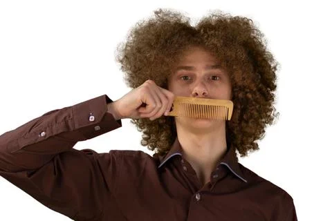 A long-haired curly-haired guy in a brown shirt on a white background uses a  Stock Photos