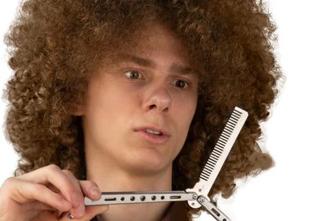 A long-haired curly-haired guy in a brown shirt on a white background uses a  Stock Photos