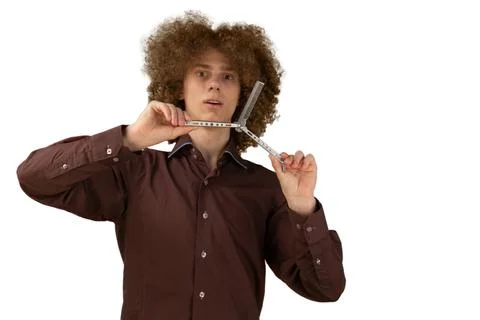 A long-haired curly-haired guy in a brown shirt on a white background uses a  Stock Photos