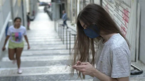 Long Haired Face Masked Guy Using Smartphone Outside Video stock 135144639