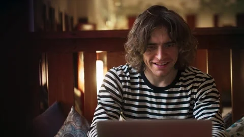 A long-haired freelancer works at his laptop in a coffee shop. Cultural Harmony Stock Footage 264070084