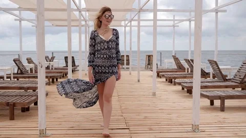 Long-haired girl in developing clothes on waterfront, young woman in glasses Video stock 80225528