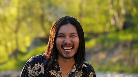 A long haired handsome hippy man laughing happily in the mountains against a Stock Footage 76001740