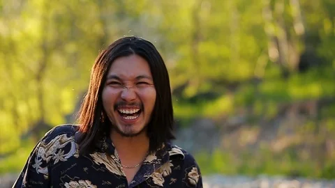 A long haired handsome hippy man laughing happily in the mountains against a Stock Footage 76001763