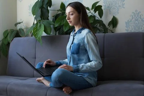 Long haired lady sitting on the couch with black laptop Stock Photos