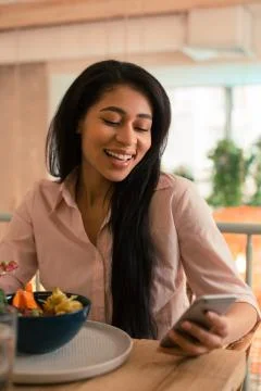 Long haired lady using smartphone while eating her lunch Stock Photos