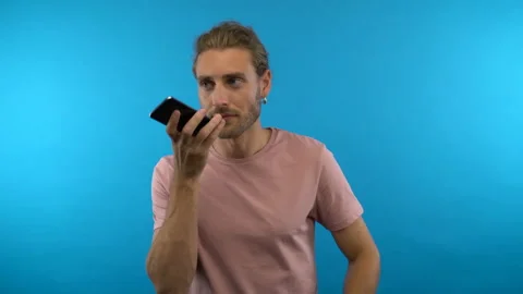 Long haired man on isolated blue background controls phone with voice / voice Stock Footage 138638394