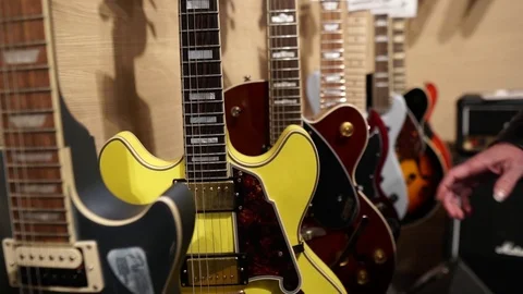 Long Haired Man with Leather Jacket checking selecting guitars in store 2 Stock Footage 124672318