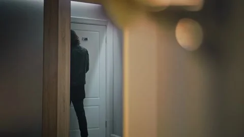 A long-haired man opens the door of a hotel room and walks in. He is dressed in Stock Footage 252274483